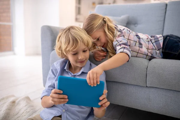 Niño y niña sosteniendo la tableta juntos, viendo algo, sonriendo — Foto de Stock