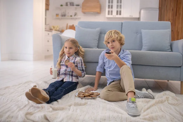 Niño y niña sentados en el suelo, viendo la televisión —  Fotos de Stock