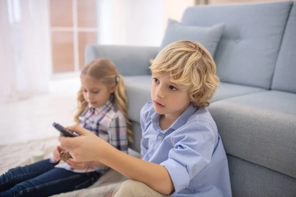 Niño y niña viendo la televisión, niño sosteniendo el control remoto —  Fotos de Stock