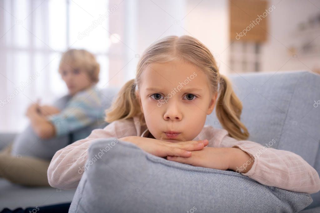 Blond cute girl with a pillow in her hands frowning