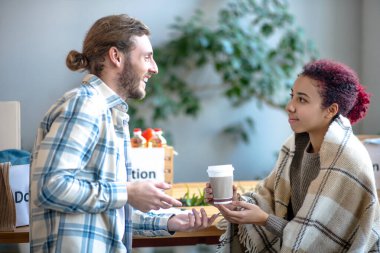 Genç adam ve kız kahve içerken konuşurken izliyorlar..
