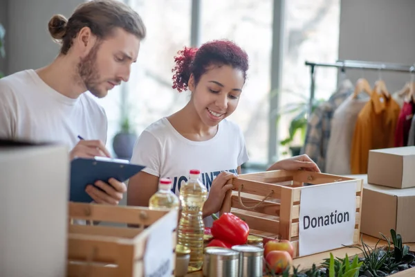 Lächelndes junges Mädchen und ernsthafter Mann mit Ordner arbeiten zusammen. — Stockfoto