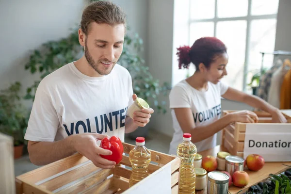 Unga volontärer fyller välgörenhetslådor med mat. — Stockfoto