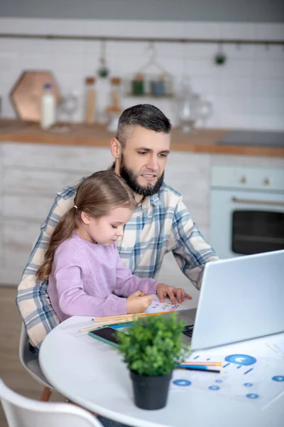 Papá joven trabajando en el ordenador portátil, hija sentada en las manos de los papás . — Foto de Stock
