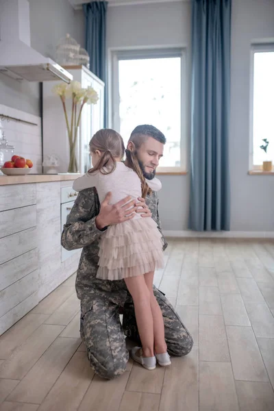 Dad in uniform hugging little daughter at home. — 스톡 사진