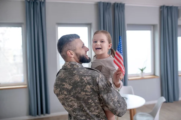 Papá sosteniendo una hija pequeña con una bandera americana . — Foto de Stock