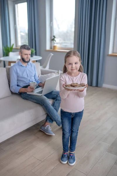 Дівчина в джинсах з тарілкою печива в руках . — стокове фото