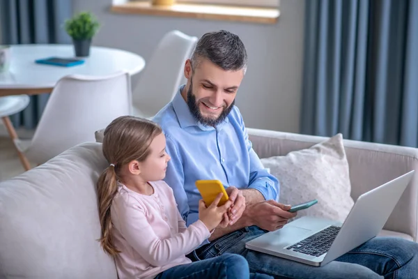 Hijita mostrando smartphone a papá joven . — Foto de Stock