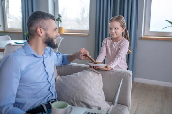 Caring little daughter treating dad with cookies. — Stockfoto