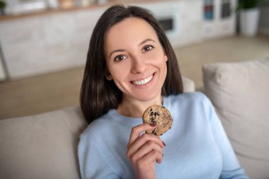 Smiling woman having a tasty cookie with chockolate drops