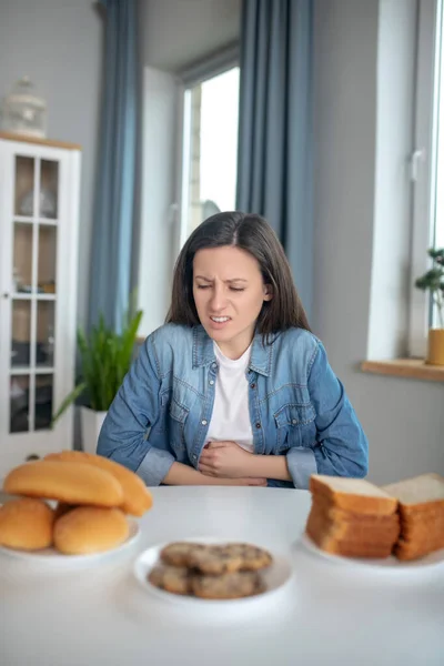 Woman eating bread having a stomach ache — Stock Photo, Image