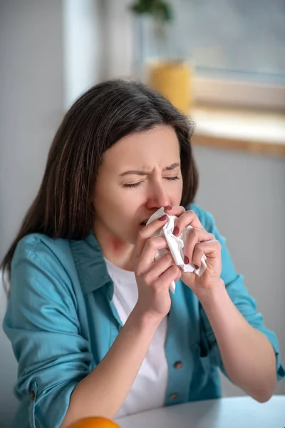 Mujer joven estornudando y usando una servilleta — Foto de Stock