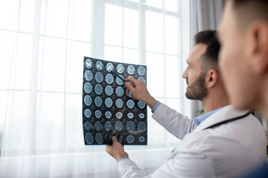 Two male doctors looking interested while analyzing MRI results