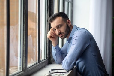 Young bearded man in blue shirt looking upset