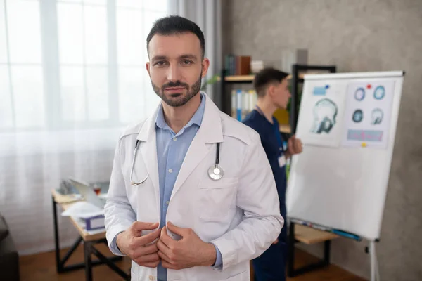 Médico joven de cabello oscuro con una túnica blanca que parece determinada — Foto de Stock