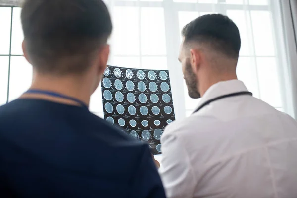 Dos médicos varones que buscan participar mientras analizan los resultados de la resonancia magnética — Foto de Stock