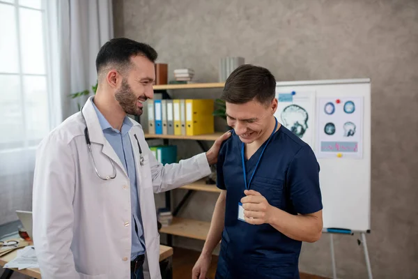 Doctor barbudo acariciando a su colega en un hombro — Foto de Stock