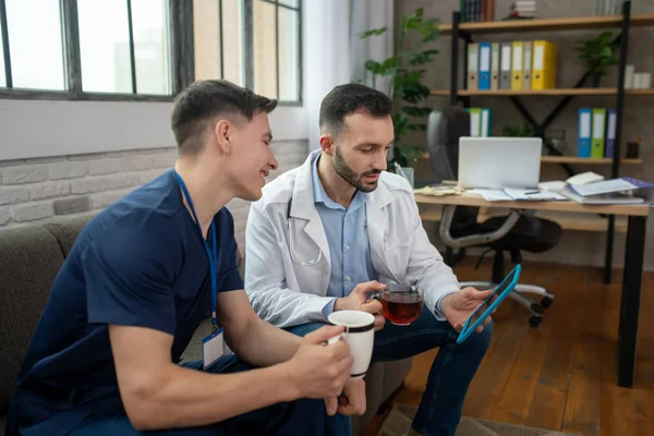 Two young doctors having tea and surfing internet — Stock Photo, Image