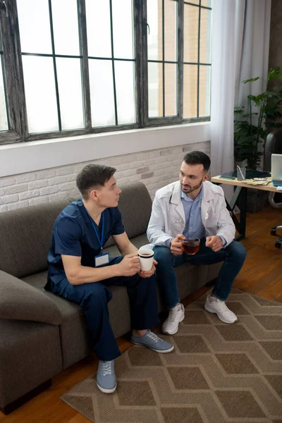 Two doctors having tea and talking during changeover — Stockfoto