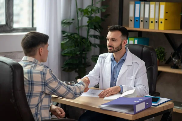 Joven médico moreno explicando el caso al paciente — Foto de Stock