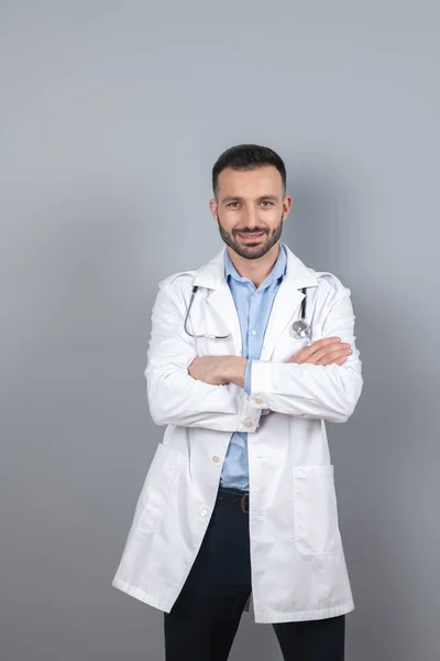 Doutor com um estetoscópio em seu pescoço em pé perto da parede — Fotografia de Stock