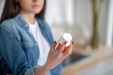 Young woman holding a container with pills