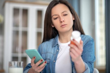 Woman looking for the instruction for drugs using her smartphone