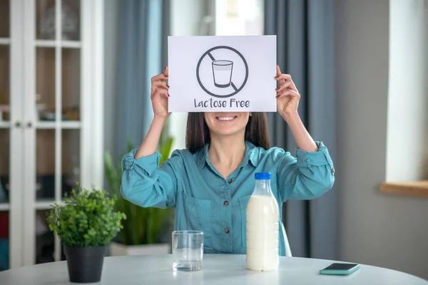 Woman holding a lactose free sign while drinking milk — ストック写真