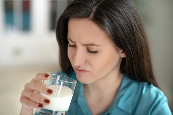 Mujer bebiendo un vaso de leche involuntariamente — Foto de Stock