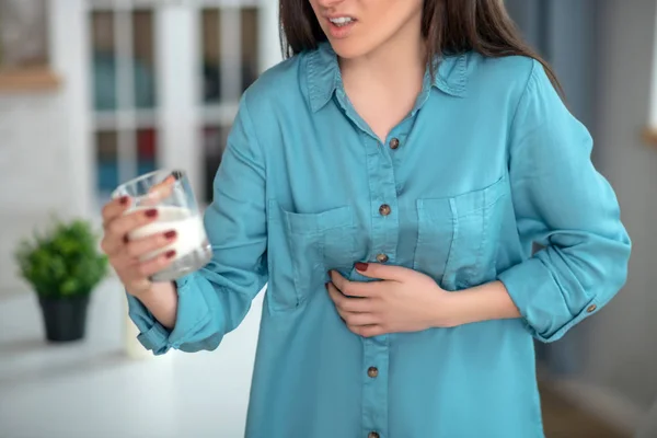 Kobieta z bólem brzucha i mlekiem do picia — Zdjęcie stockowe