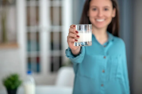 Улыбчивая женщина держит стакан молока — стоковое фото