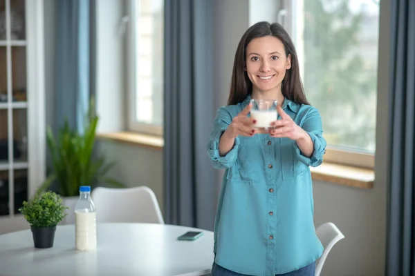 Smiling woman holding a glass of fresh milk — Stok fotoğraf