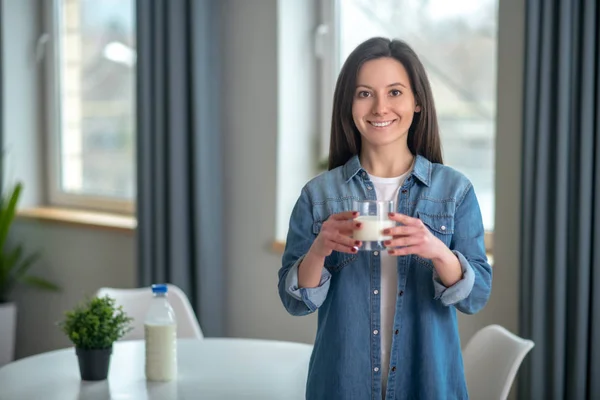 Femme souriante tenant un verre de lait — Photo