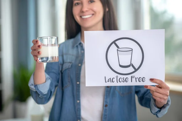 Mujer con intolerancia a la lactosa que sostiene un signo libre de lactosa —  Fotos de Stock