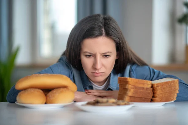 Vrouw kijkt naar de borden met broodjes en broodjes — Stockfoto