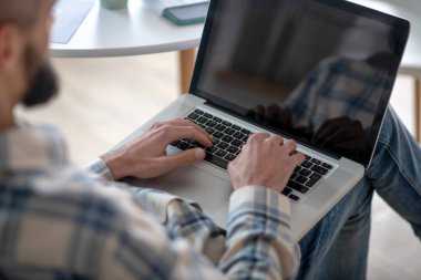 Man working on a netbook typing text.