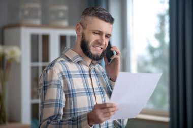 Young smiling man talking on a smartphone at home.