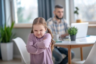 Offended little girl standing in the middle of the room.