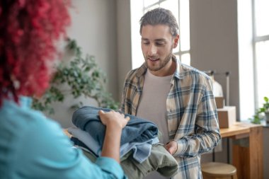 Ekose gömlekli genç bir adam ve katlanan bir kız.