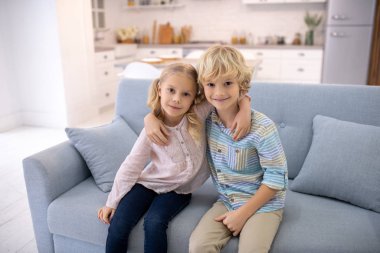 Yan yana oturan ve sarılan iki şişko çocuk.