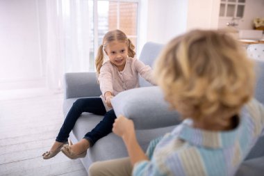 İki sarışın çocuk kanepe yastıklarını kenara çekiyor.