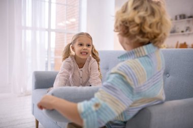 Kanepede yastıklarla oynayan ve sinirli görünen iki sarışın çocuk.