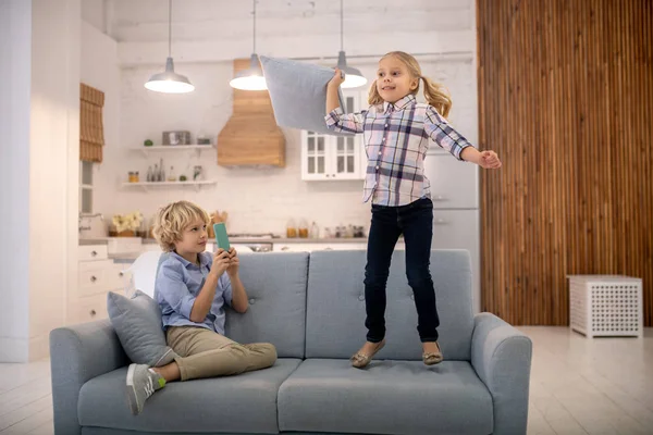 Cute blond girl jumping on the sofa