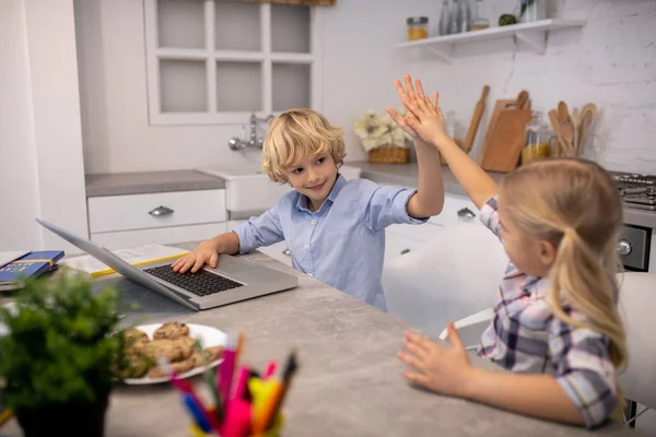 Dos niños sentados en la mesa y haciendo chocar los cinco — Foto de Stock