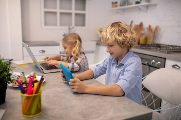 Zwei Kinder sitzen am Tisch und schauen interessiert zu — Stockfoto