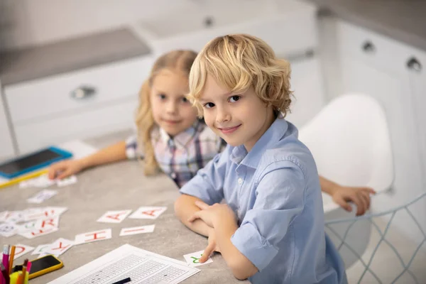 Duas crianças loiras colocando cartas com letras na mesa e olhando satisfeito — Fotografia de Stock