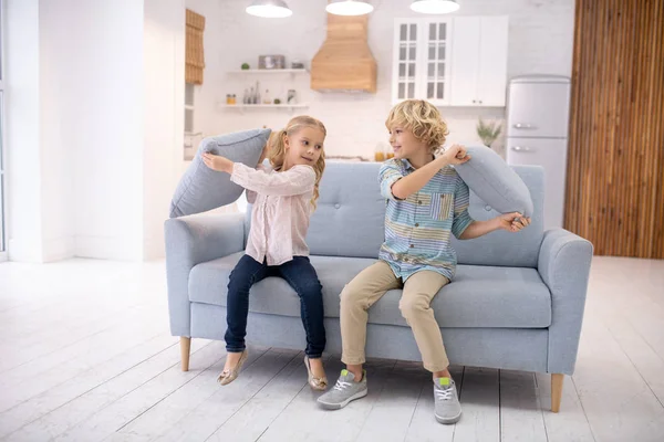 Dvě děti bití navzájem s polštáři a pocit, těší — Stock fotografie