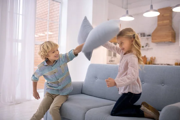 Two kids beating each other with pillows