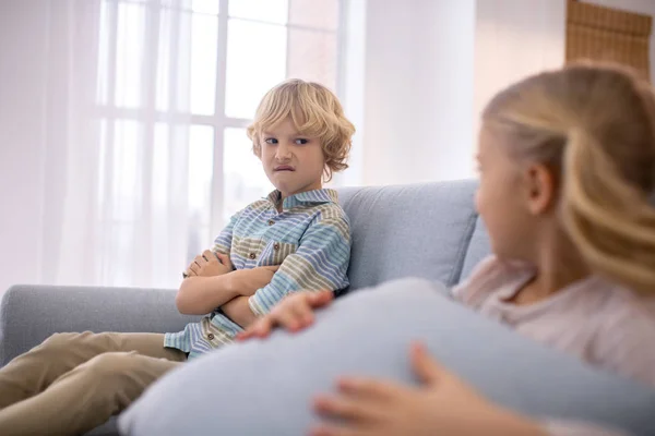 Blond kids sitting on the sofa and looking at each other — Stock Photo, Image