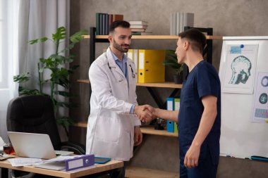 İki genç doktor personel odasında el sıkışıyor.